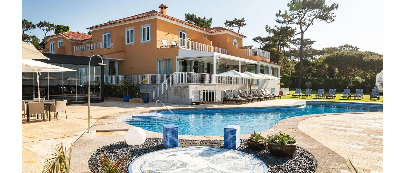 Mustard building with a floor-to-ceiling gym, outdoor restaurant terrace, swimming pool, Jacuzzi and tree-lined lawn