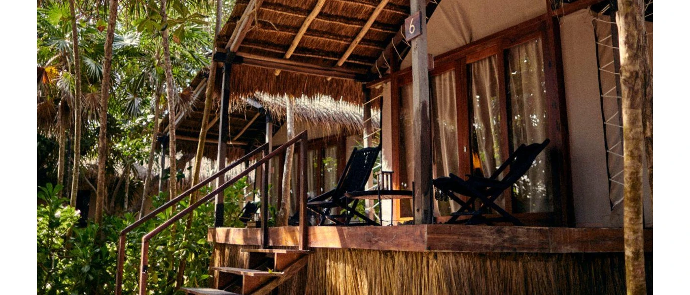 Palapa-roofed hut with a wood-decked terrace and steps leading into the jungle