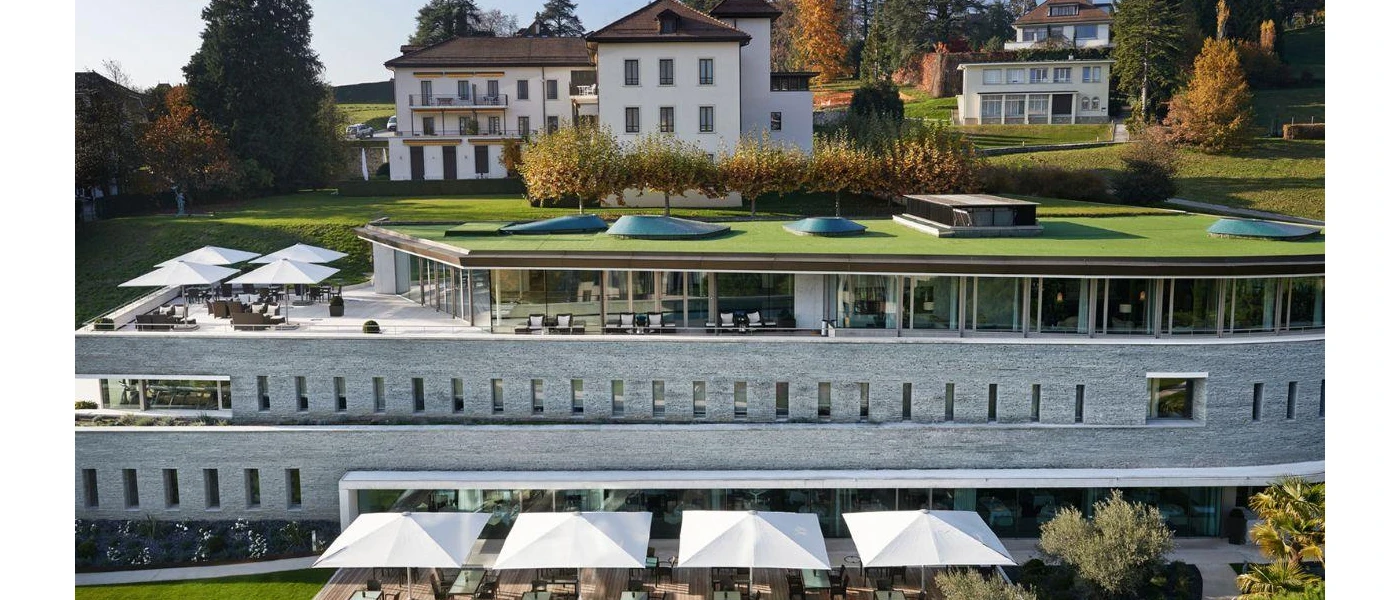 Clinique La Prairie's exterior, pretty multi-storey white buildings with tiled rooftops, manicured lawns, glass-fronted facades and staggered terraces