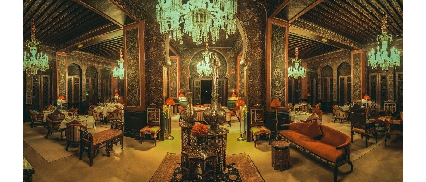 Decadent room with chandeliers, patterned pillars, and terracotta sofas