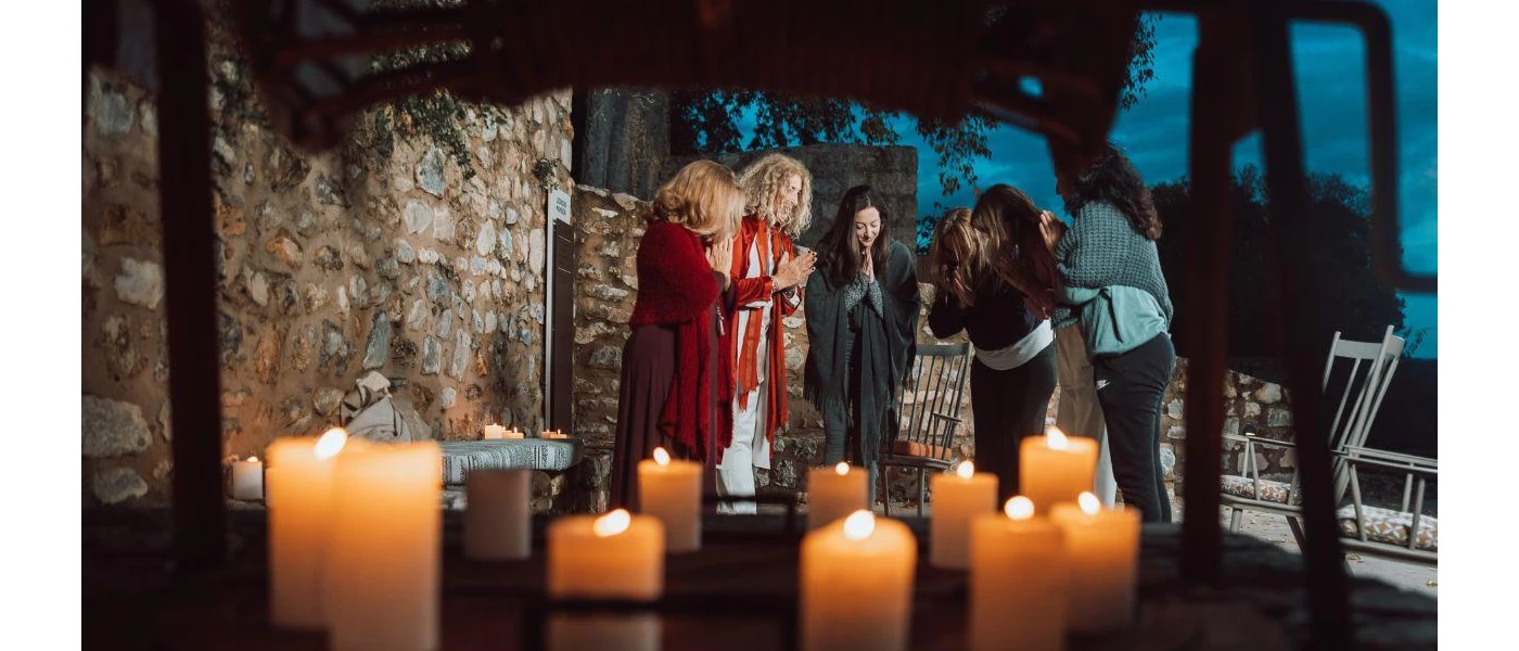 Group of woman bow their heads with their hands clasped in front of them with candles in the background