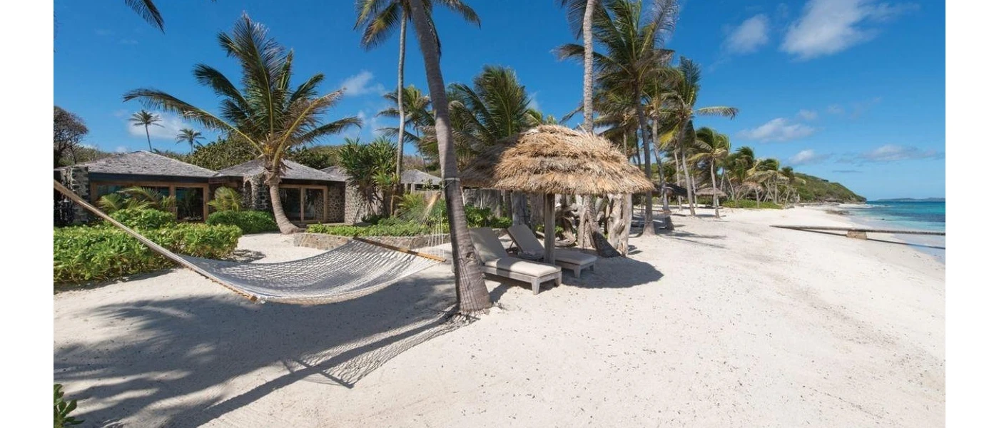 White sand, thatched umbrella, straw hammock and palm trees