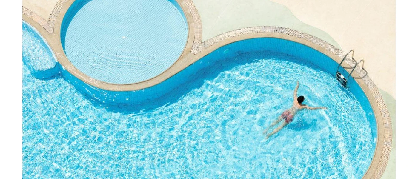 Swimming pool with a separate circular shallow section in a sunny terrace