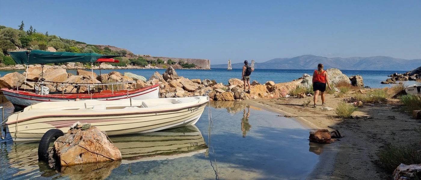 Small cove with a fishing boat, and two people admiring the surrounding sea views