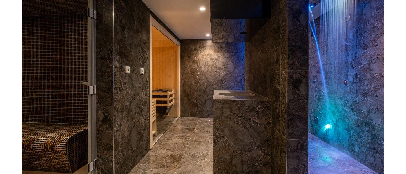 Spa with grey marble walls, blue LED lighting, a sauna and tiled steam room