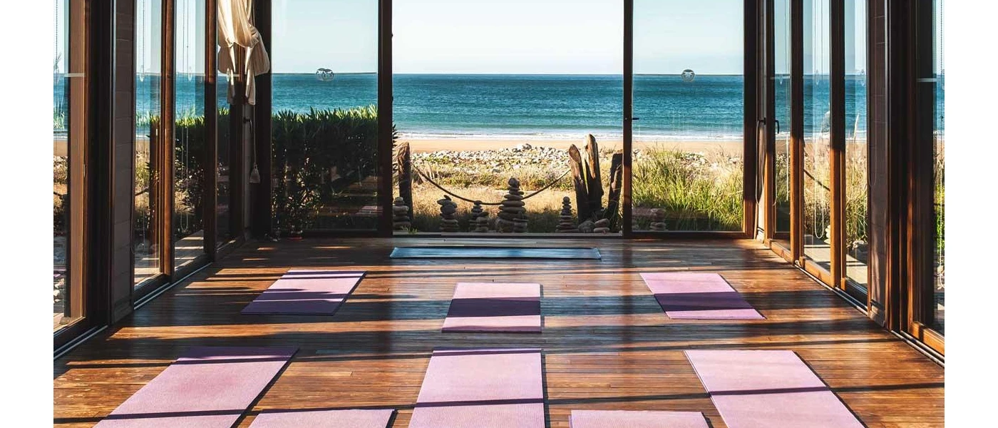 Room overlooking the sea laid out with purple yoga mats on a sunny day