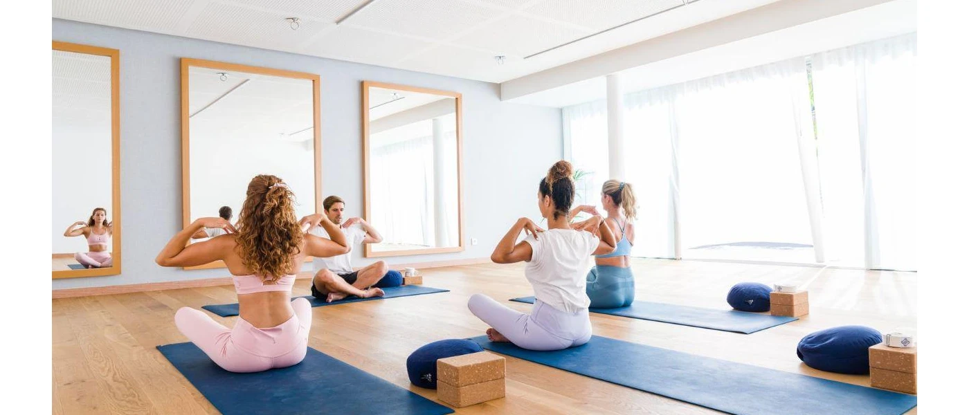 Women in active wear on mats in a fitness class in a well-lit studio 
