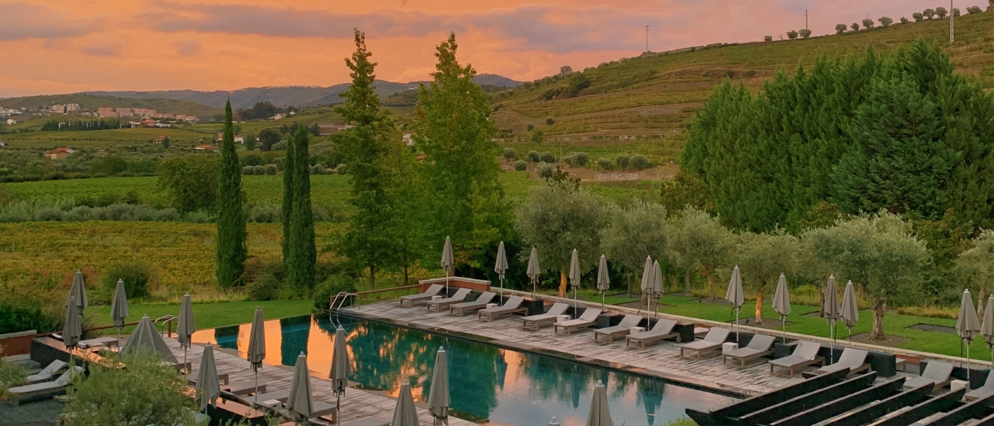 Hotel outdoor swimming pool overlooking countryside with pink sky