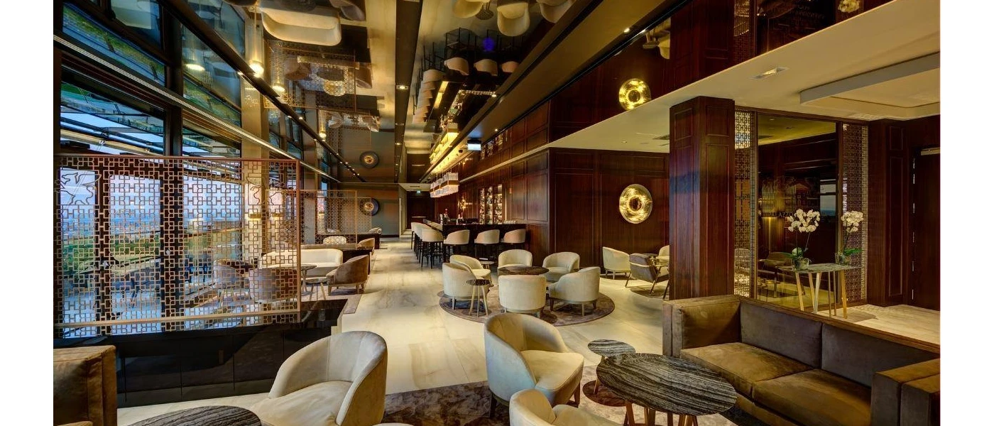 Sleek seating area with dark wood walls, cosy neutral armchairs and sofas, and velvet rugs