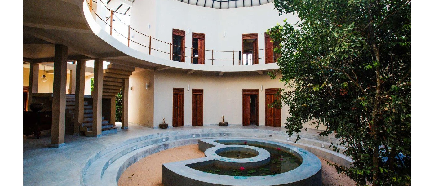 Circular pond in a central courtyard, surrounded by a tree and wooden doors over two levels