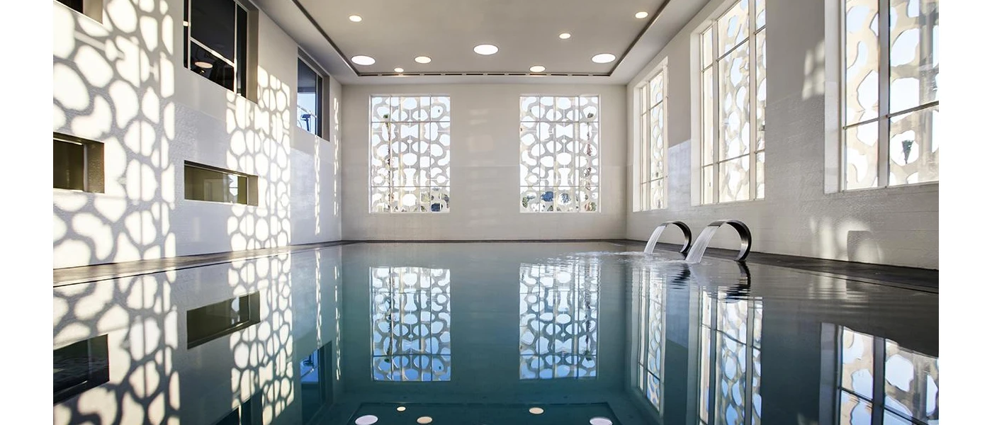 Indoor pool with spotlights and a wall with a geometric pattern