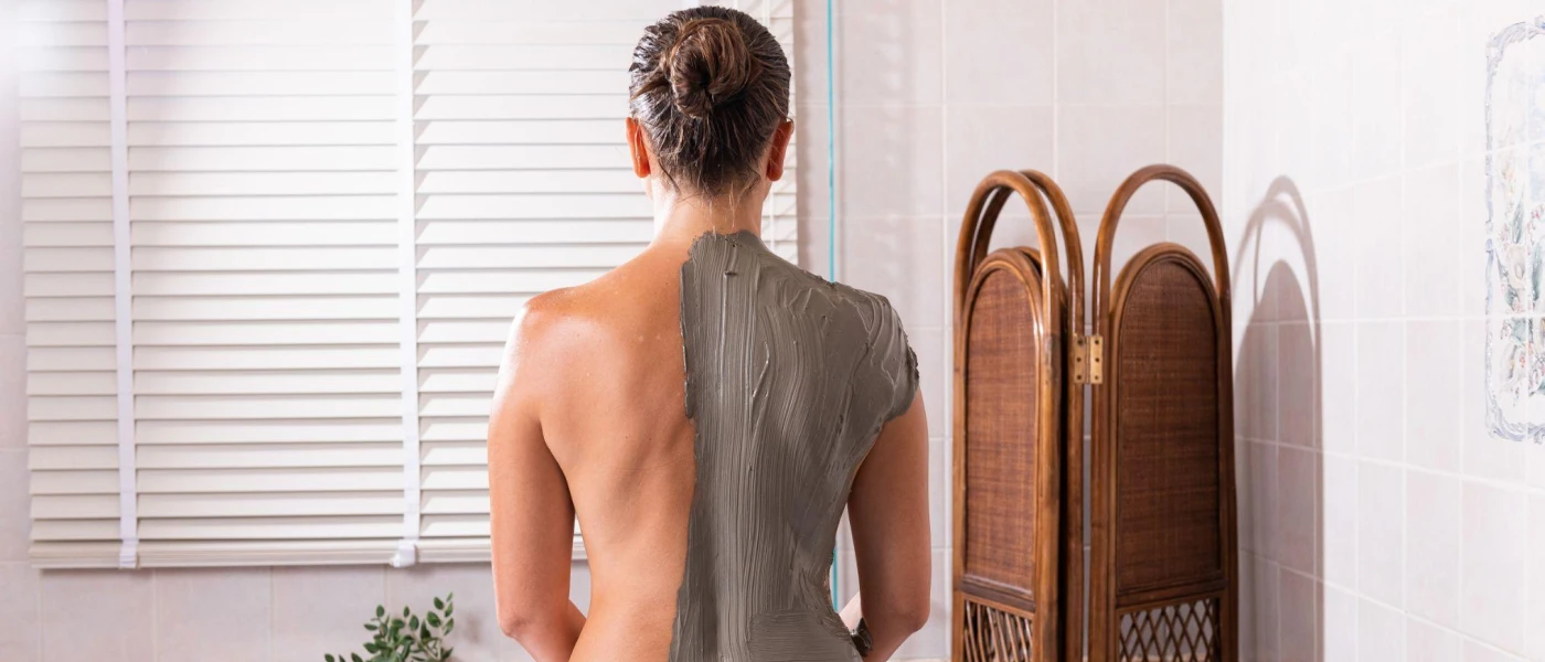 Woman standing with half of her back covers in mud
