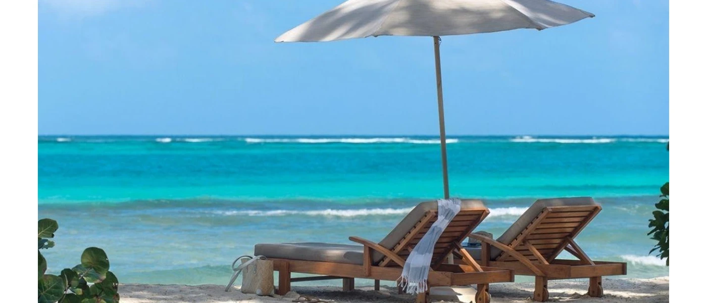Wooden loungers and a white umbrella overlooking the ocean