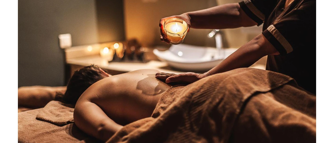Woman lying down in a softly lit room receiving a massage with candles in the background