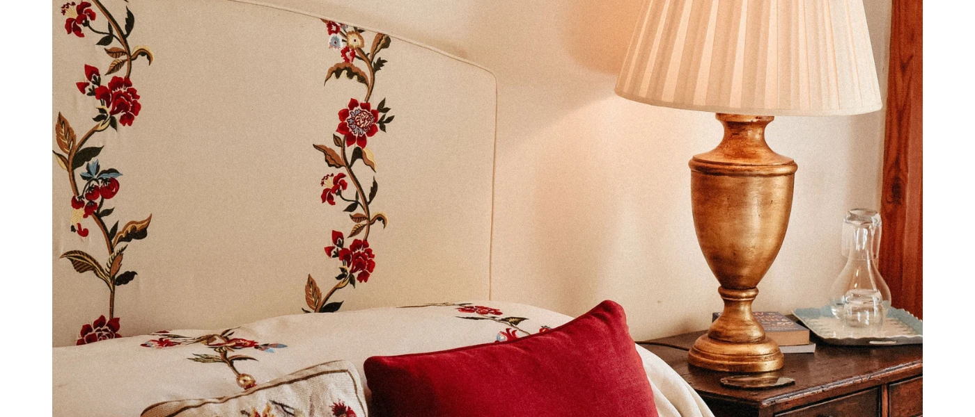 Rose-patterned headboard, red cushion and nightstand with lamp