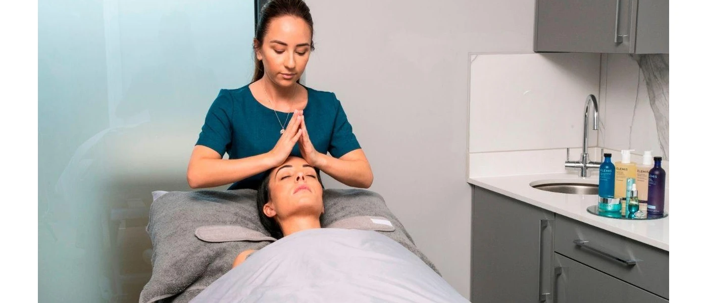 Woman lying down with her eyes closed as a consultant massages her head