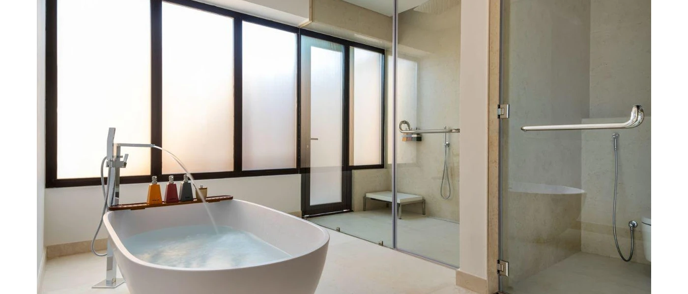 Bathroom with a large standalone tub with running water, a walk-in shower with glass doors and frosted windows