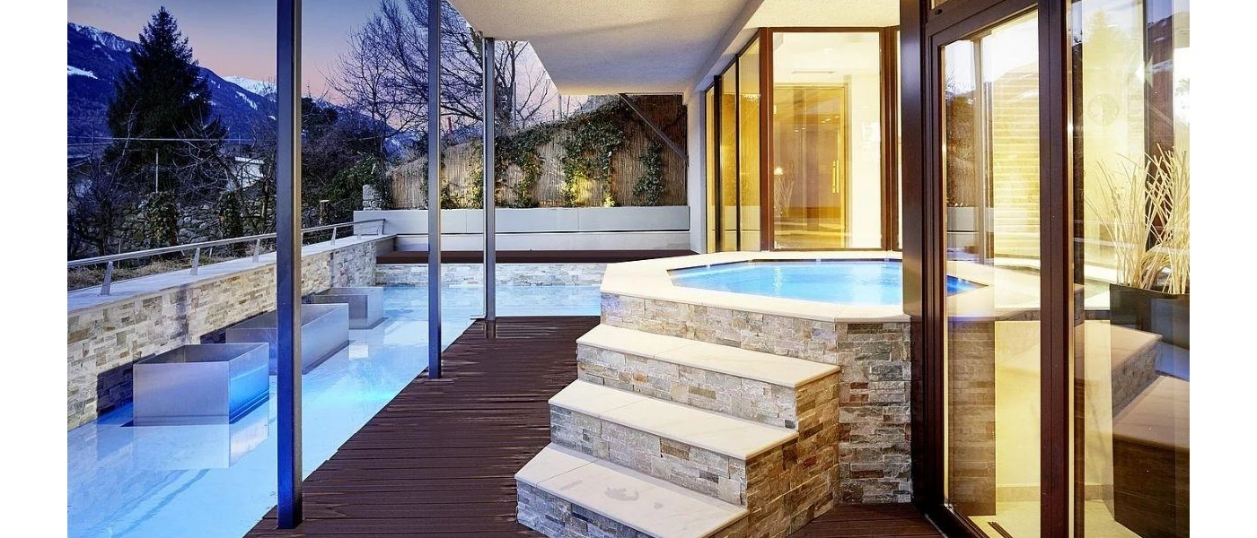 Wooden terrace with a surrounding pool, stepped hot tub and views of the surrounding mountains