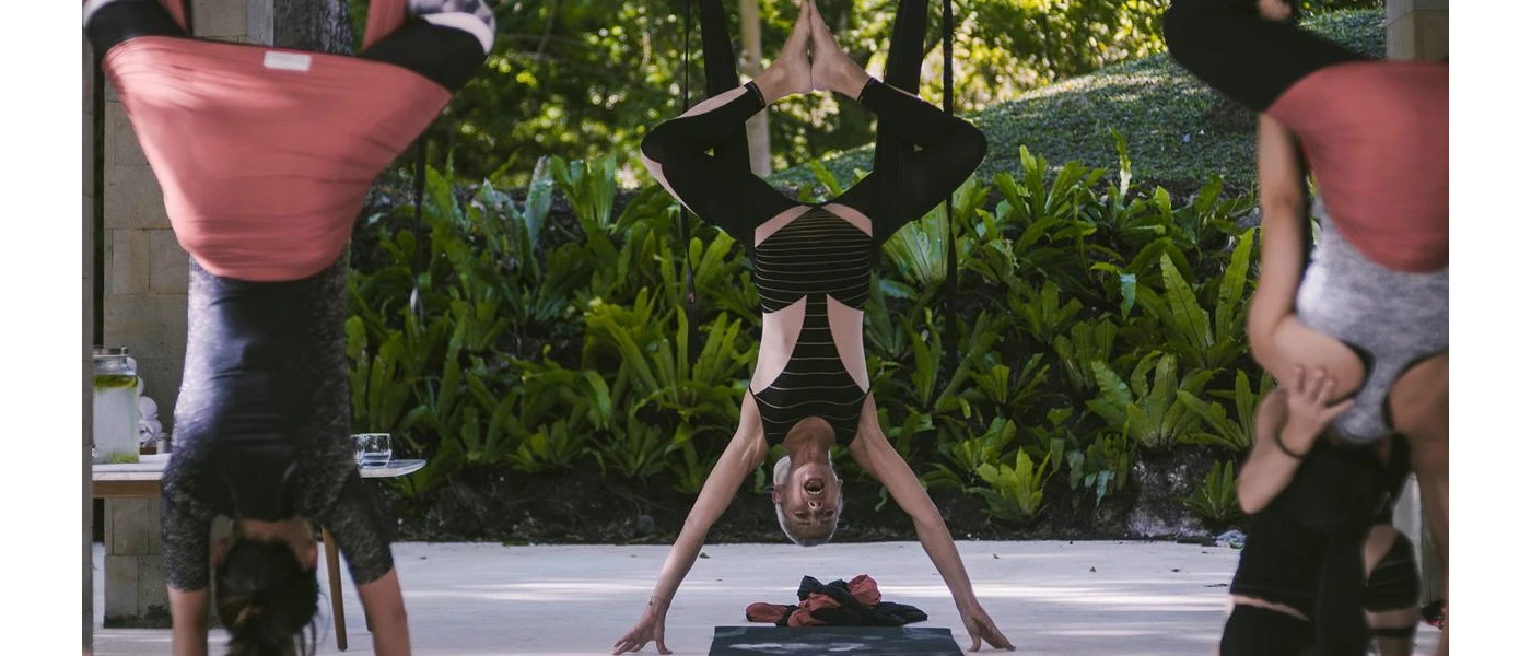 Group in yoga poses on a terrace overlooking lush greenery