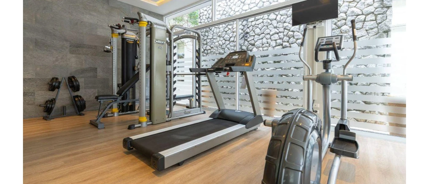 Airy gym studio with full-length windows, a treadmill, bike and weights and wooden flooring