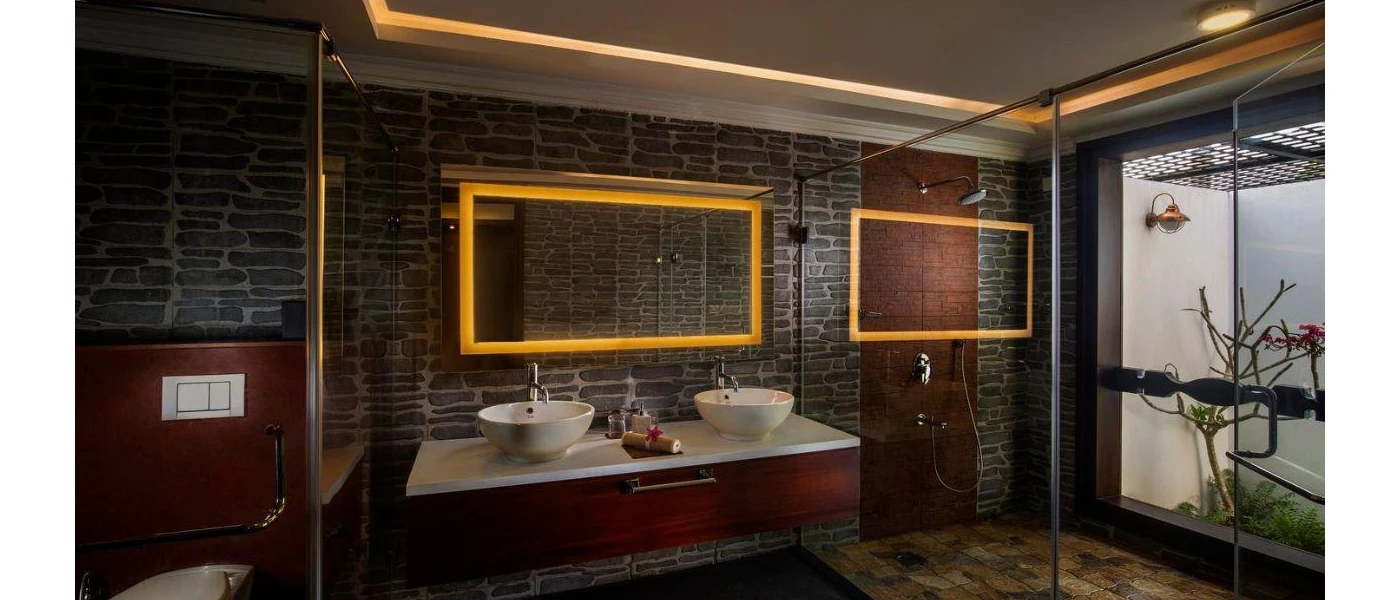 Bathroom with black stone walls, a dark-wood vanity unit with twin sinks, and a large glass-doored shower 
