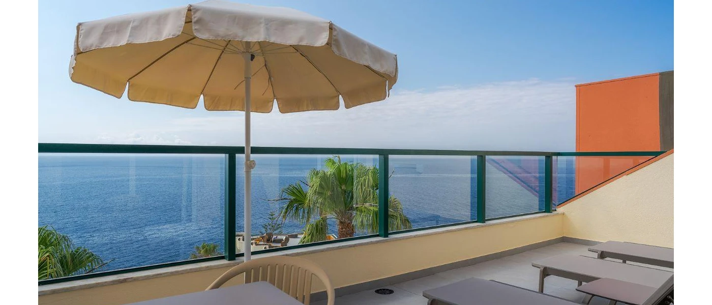 Balcony with black railing, loungers and umbrellas and a view of the ocean