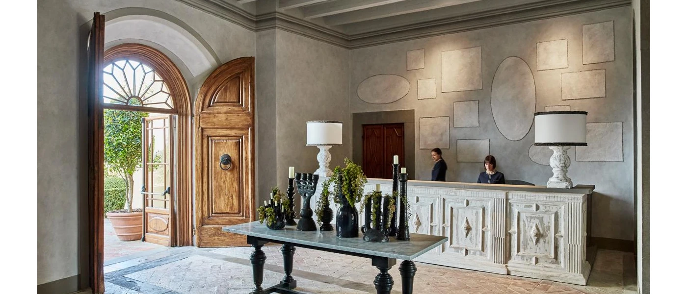 Hotel lobby with grand wooden doors, stone walls and a table filled with black candlesticks