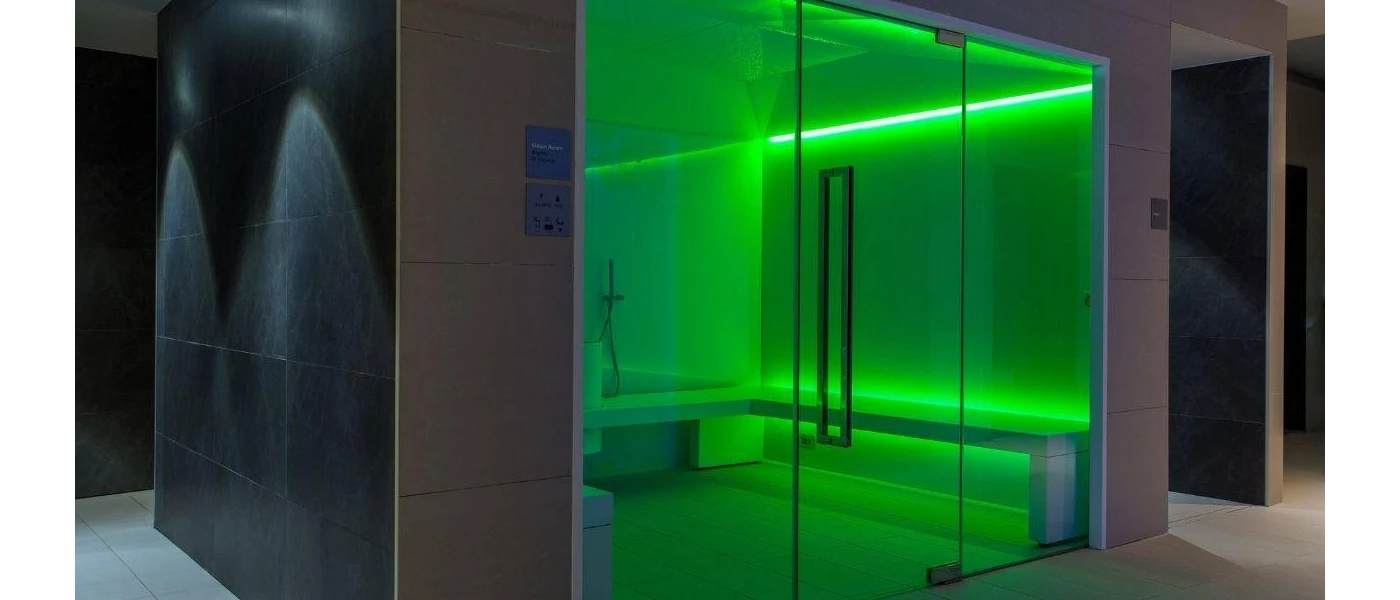 Green-lit steam room with a glass door 