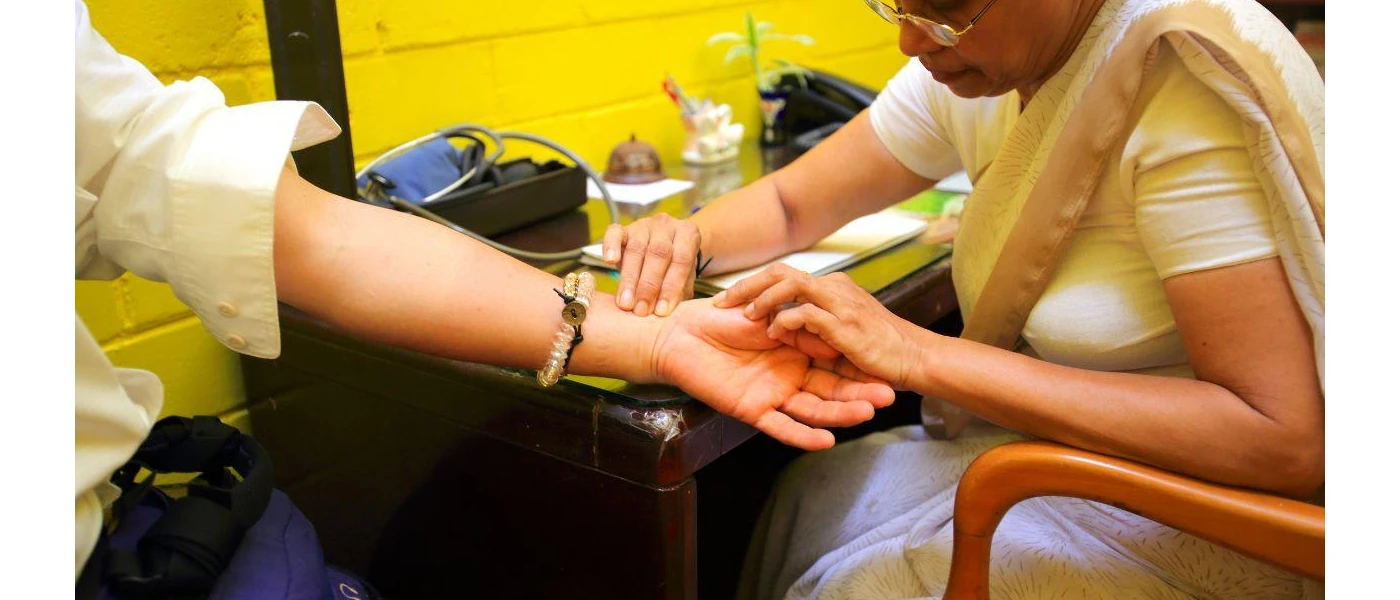 Ayurvedic therapist studies a guests hands