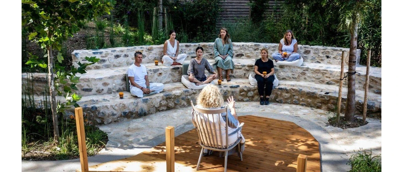 Group of people sit on cobbled stone layered seating as a woman carries out a talk in front of them