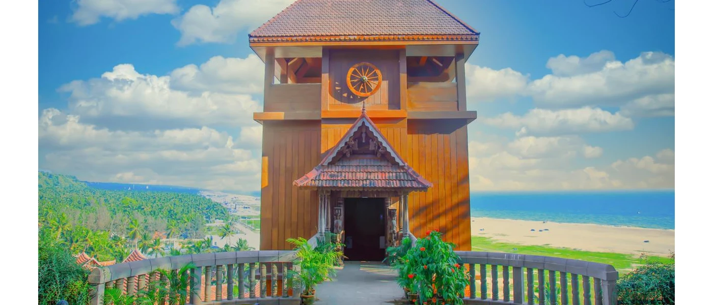 Wooden tower with a triangular terracotta roof on a hilltop overlooking golden sands and the ocean