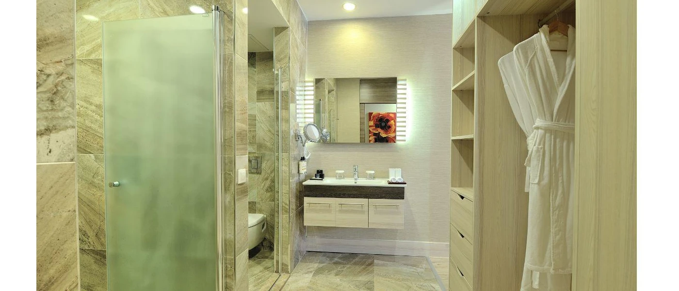 Marble-look bathroom with a shower, vanity unit and wooden shelving, white hung bathrobe and wall mirror