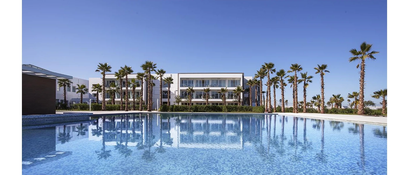 White building overlooking a large swimming pool and palm trees