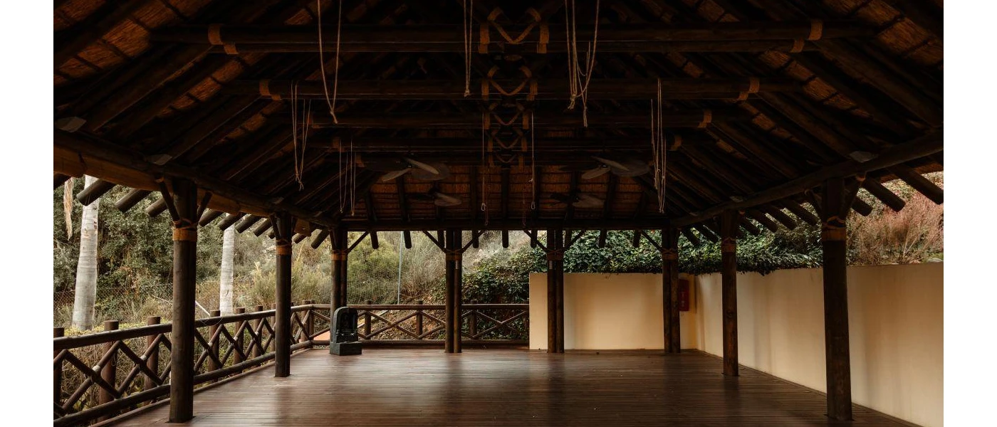 Open-sided pavilion with a wooden ceiling and floors and a view of tropical gardens