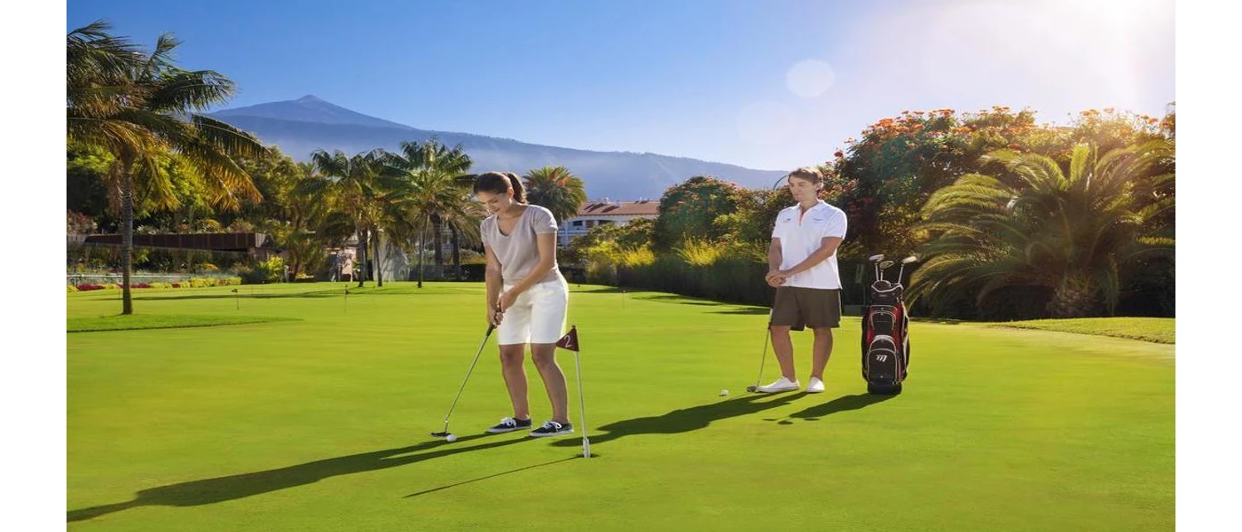 Man and woman enjoy golf under a sunny sky with Mount Teide in the background 