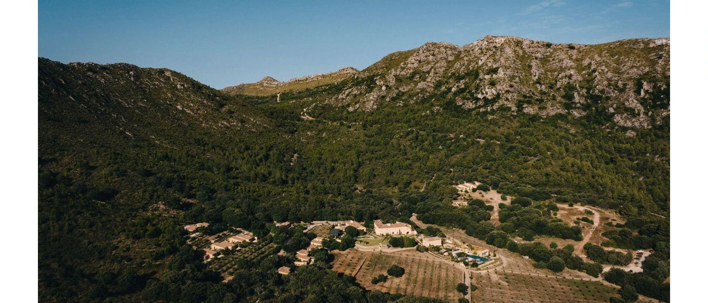 Mountains and hills cloaked in greenery, giving way to buildings and fields