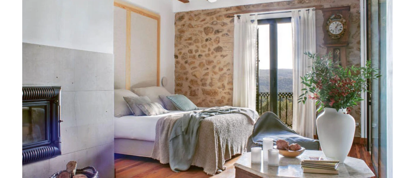 Traditional farmhouse bedroom with white bedding, cobbled stone walls and a wooden floor