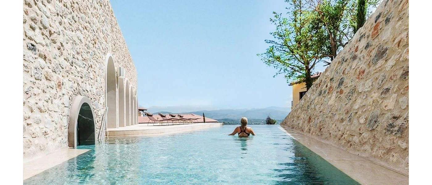 Woman in a black swimsuit admires the view in an outdoor infinity pool