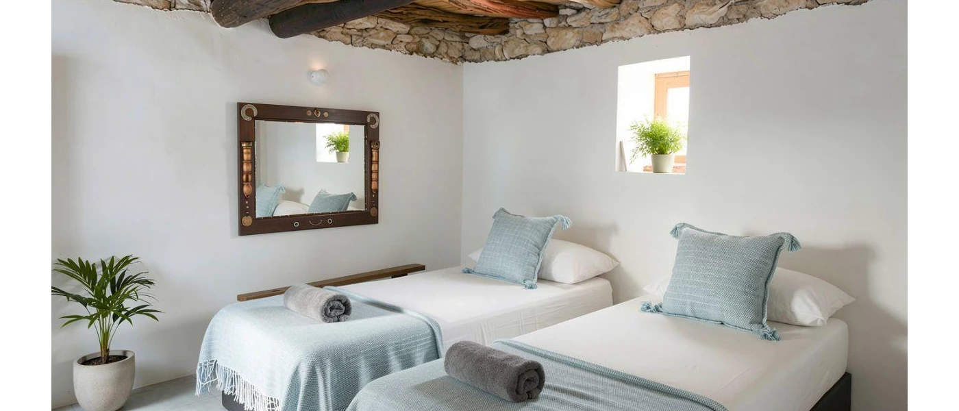 Twin beds dressed in white and powder blue, a cobbled stone ceiling an wooden wall mirror