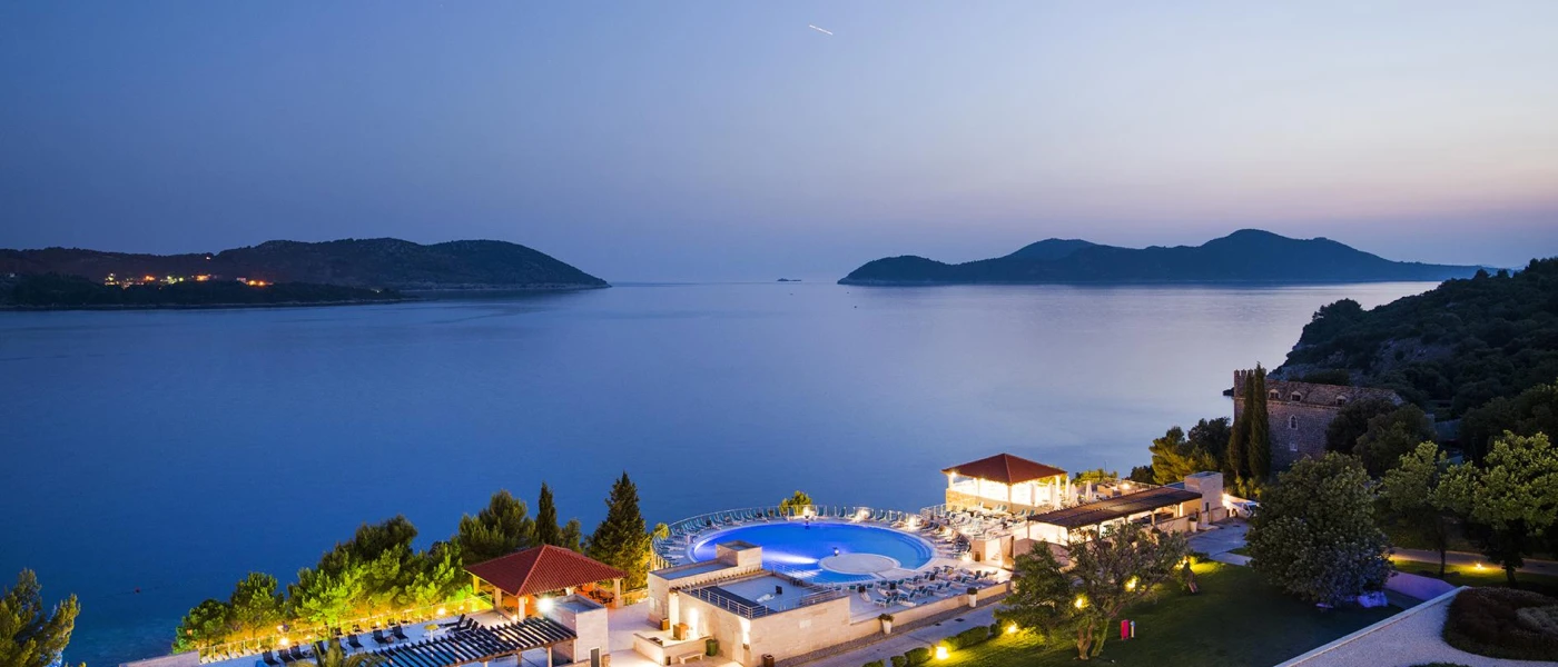 Resort after-dark, with the swimming pool and landscaped grounds lit up with a view of the sea