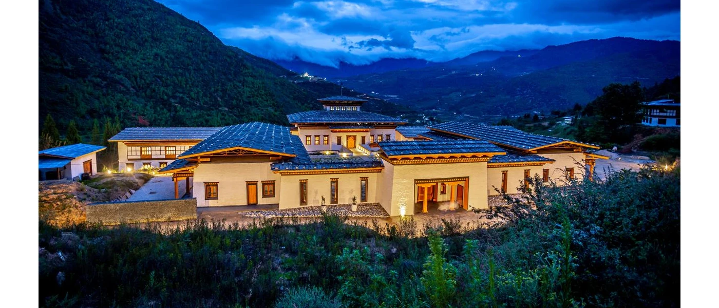 Low-rise stone building nestled among hills under a cloudy sky at twilight