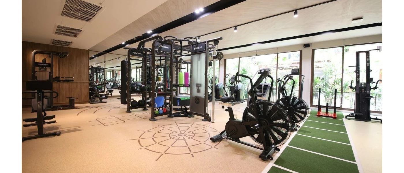 Gym with bikes, weight machines and benches and floor-to-ceiling windows