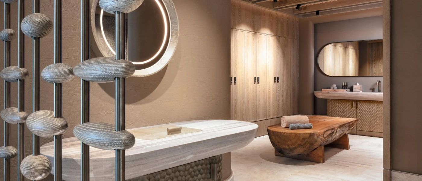 Wellness area with neutral walls, soft lighting, shell sculptures, a vanity unit and a wooden table with towels folded on it