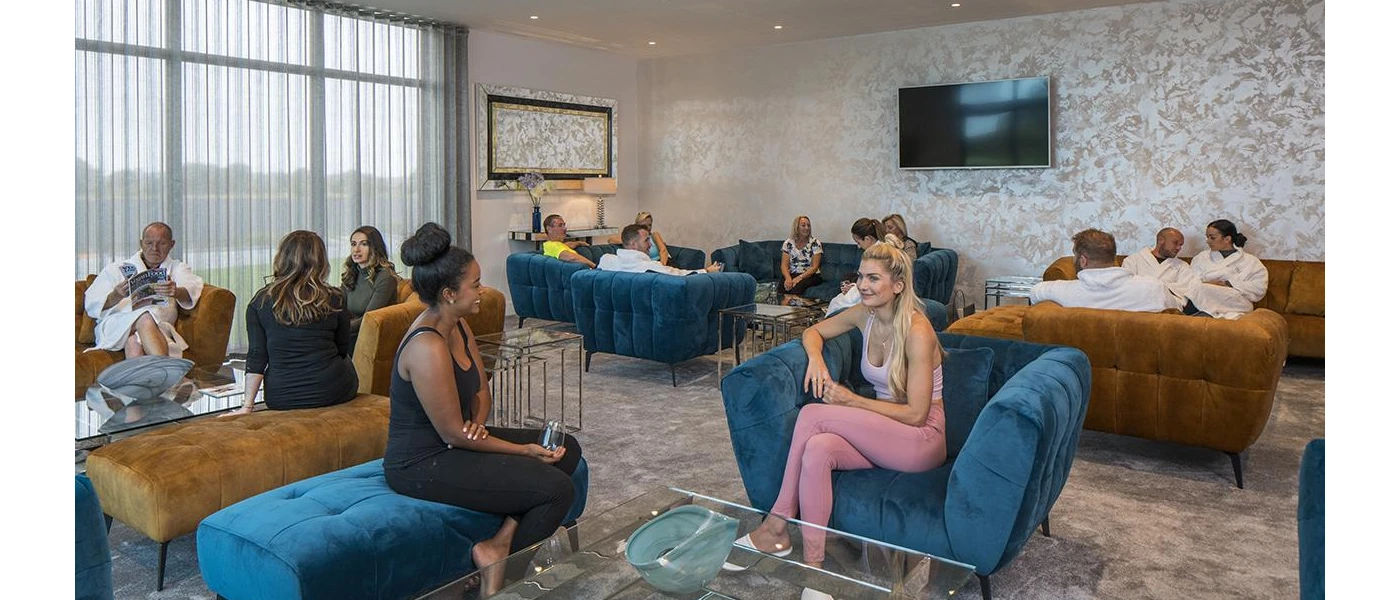 Busy lounge with blue and brown sofas and a TV on the wall