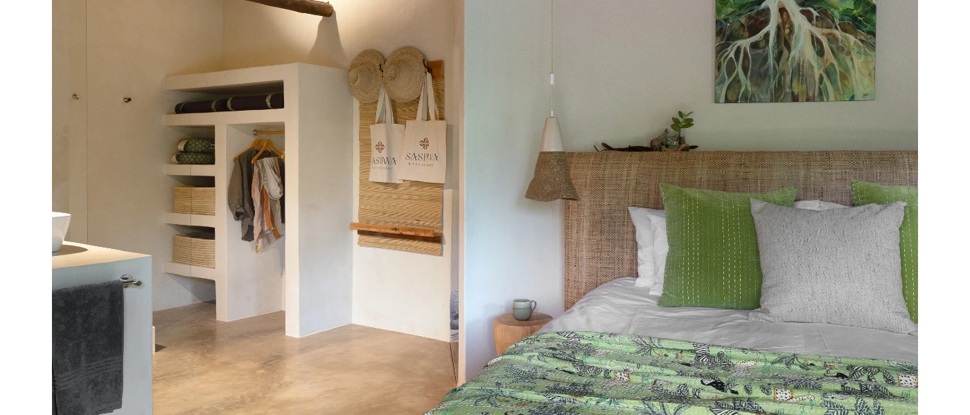 Hotel room with white walls and a wardrobe, a rattan headboard and green and white bedding, plus nature-inspired wall art above