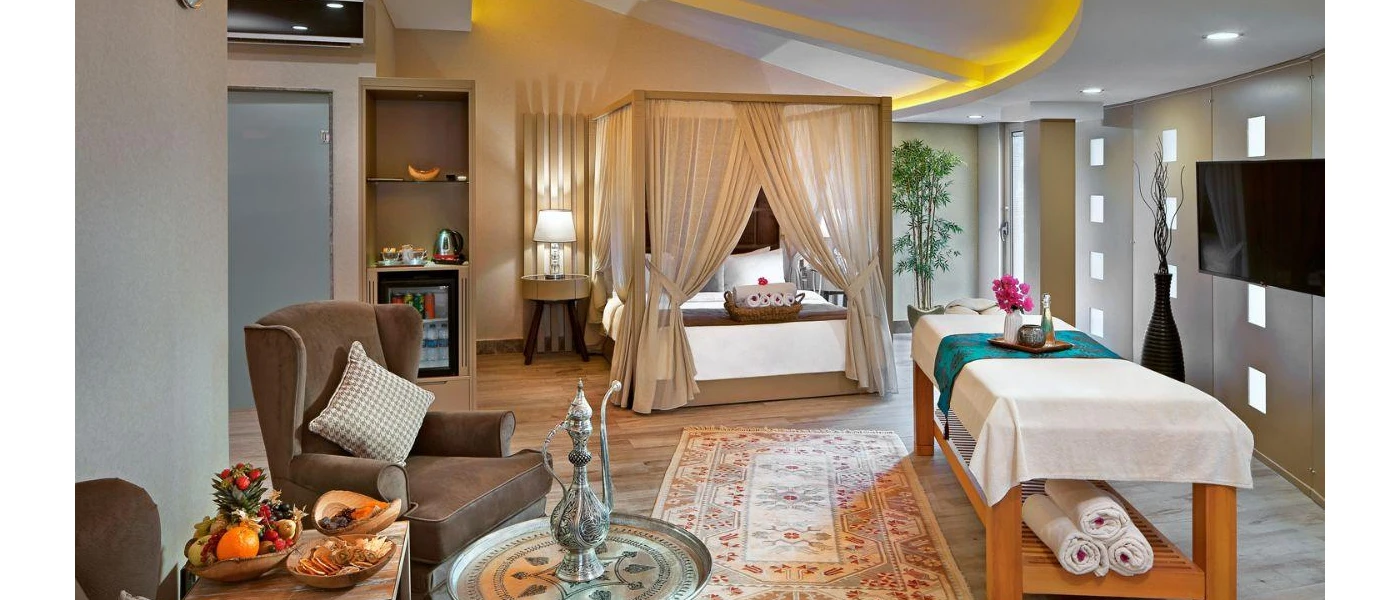 Cosy room with a four-poster bed, treatment bed, tray of Turkish tea, brown armchairs, a wall-hung TV and a traditional rug