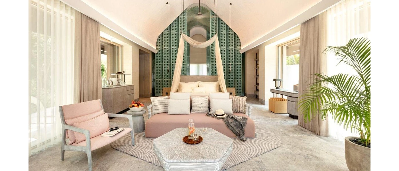 Bohemian-style villa interior, with a neutral colour scheme, blue feature wall, a potted plant, bed and sofa area