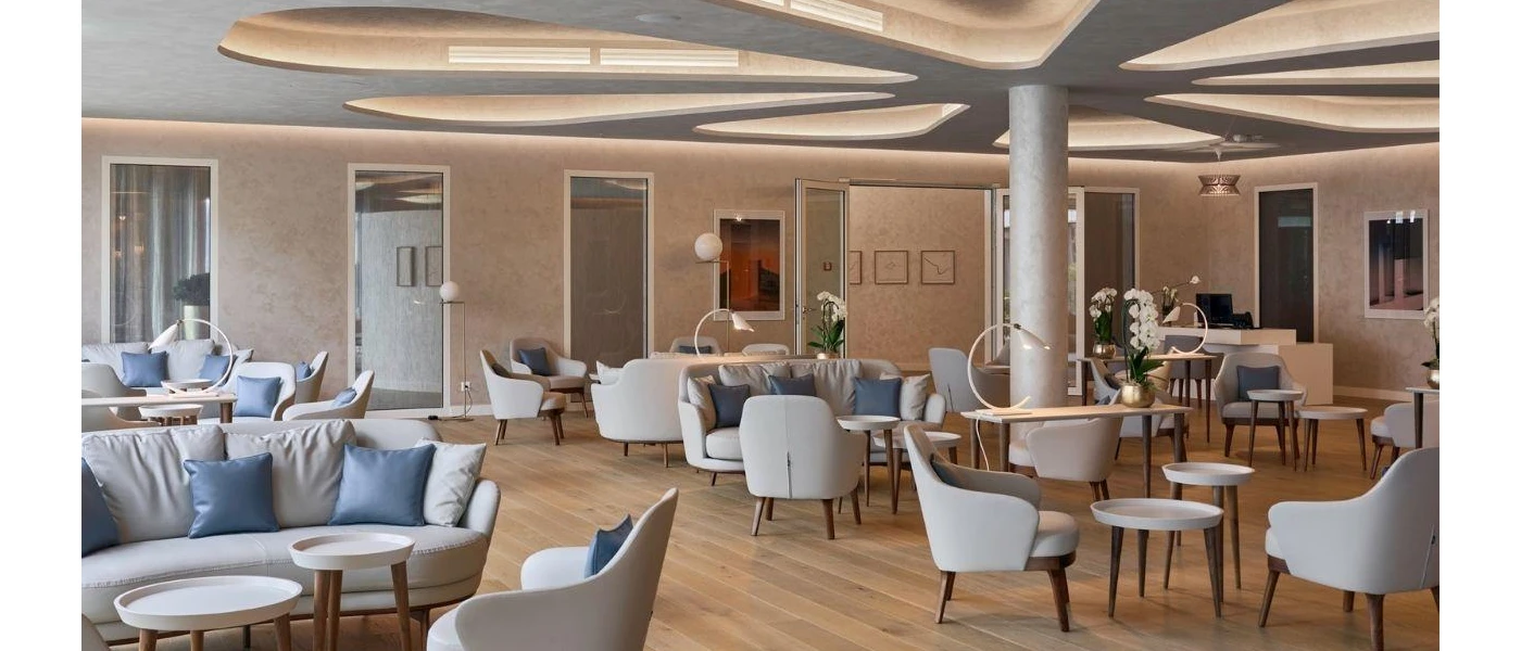 Neutral lounge-style room with grey chairs, blue cushions and potted orchids