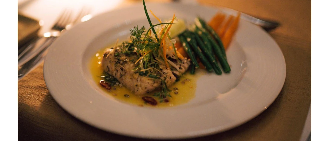 I dish of fish and fresh steamed vegetables in a yellow sauce 