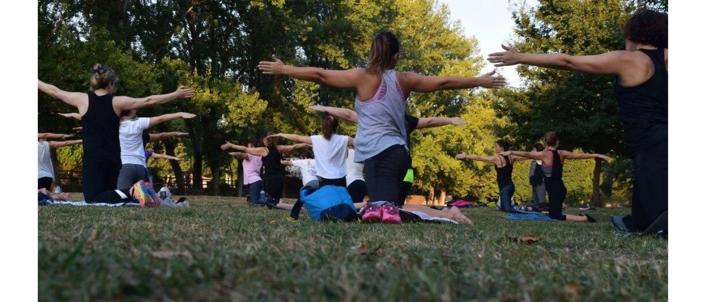 Group participating in an outdoor fitness session with outstretched arms